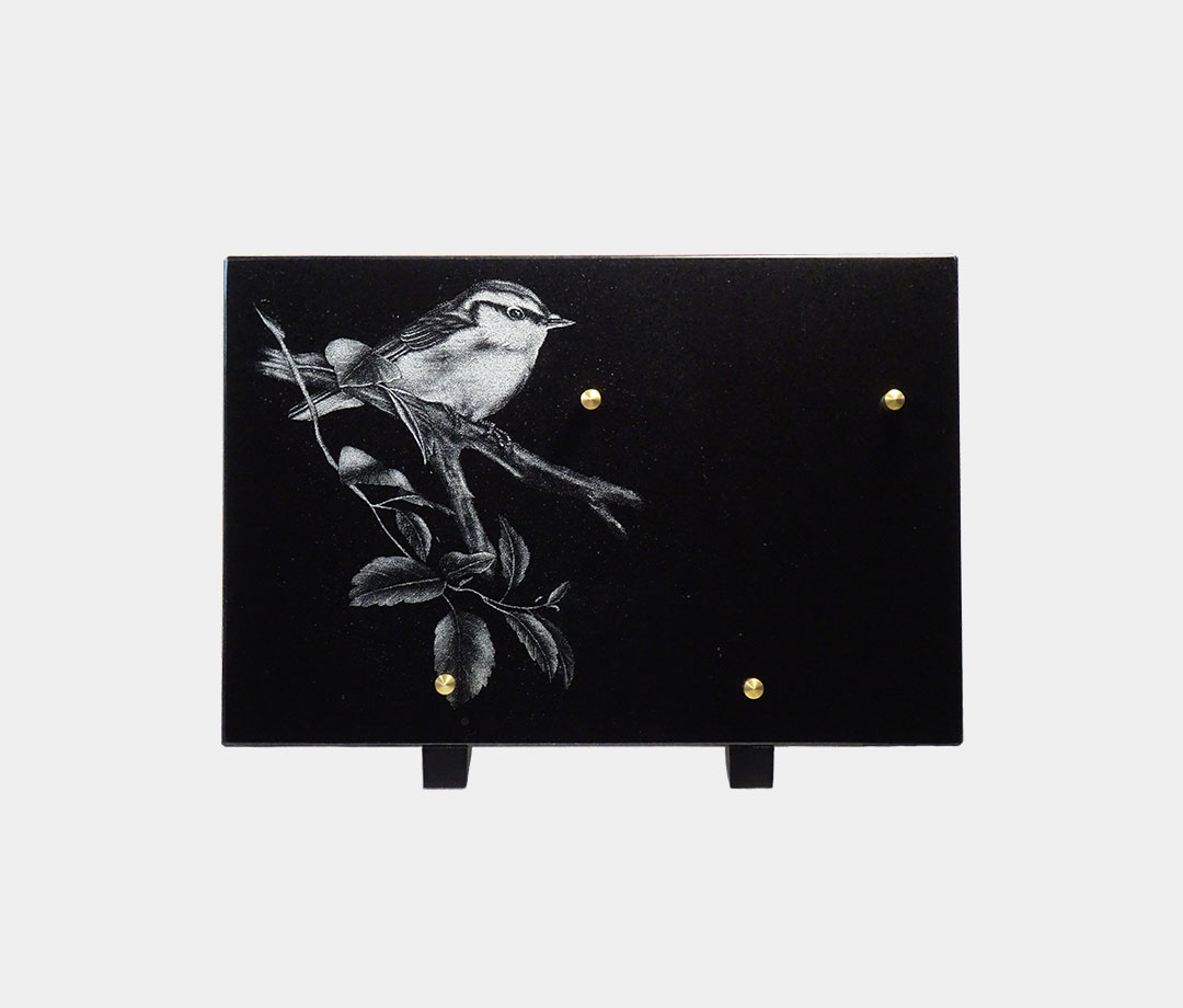 plaque funéraire moderne illustrée d'une gravure d'un oiseau sur sa branche